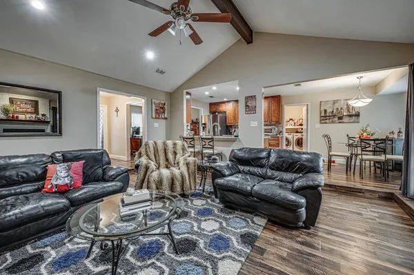 a living room with furniture and a view of dining hall with wooden floor