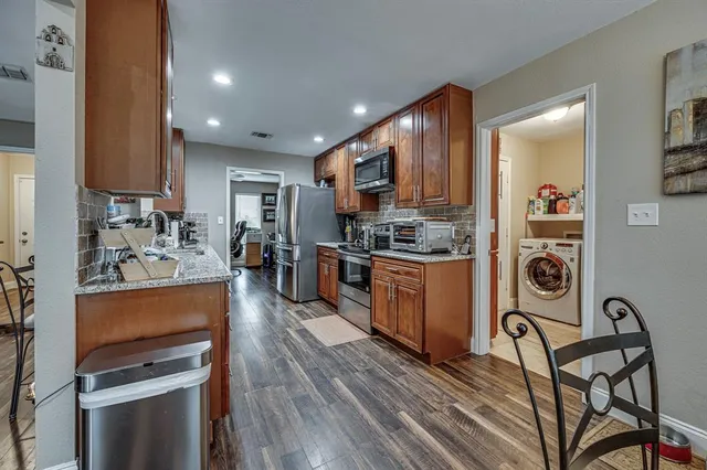 a kitchen with stainless steel appliances kitchen island granite countertop a stove a sink and a refrigerator