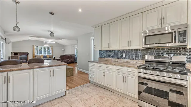 a kitchen with stainless steel appliances granite countertop a refrigerator a sink a stove and a refrigerator with wooden floor