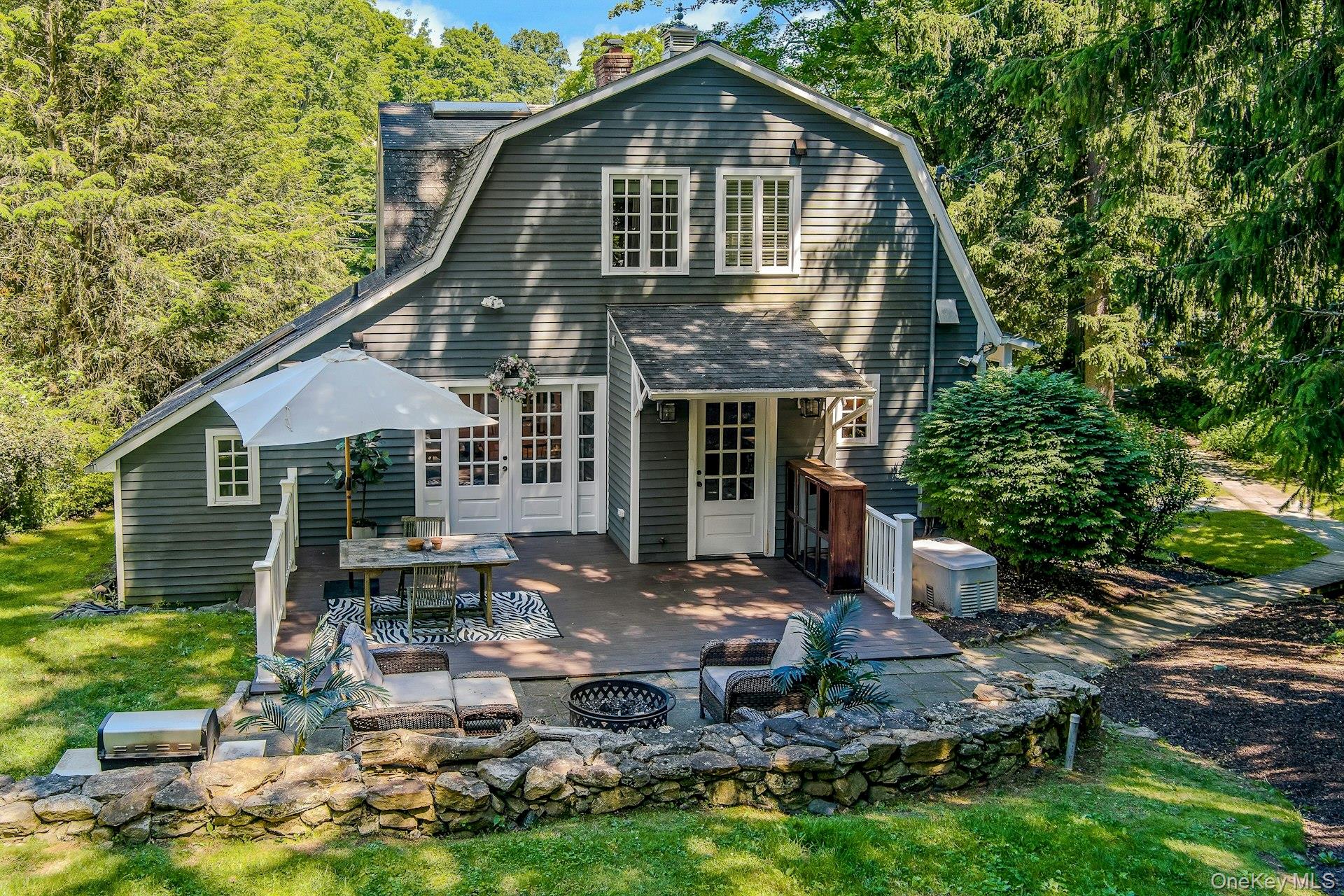 65 Douglas Road Chappaqua, NY 10514 - Photo 29 of 41 A beautiful stone patio creates the perfect outdoor setting for relaxing, dining, and entertaining around the fire pit, surrounded by the natural beauty of the property.