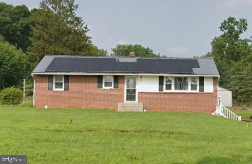 a front view of house with yard and trees in the background