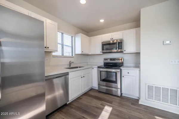 a kitchen with granite countertop a refrigerator and a stove top oven
