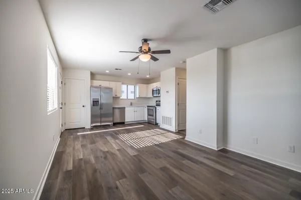 an empty room with wooden floor ceiling fan and windows