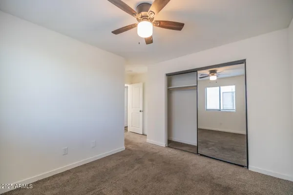 an empty room with closet and a ceiling fan