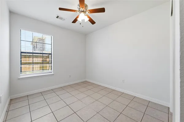 an empty room with windows and chandelier fan
