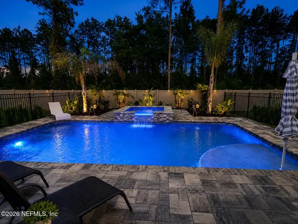a view of a swimming pool with lawn chairs and wooden fence