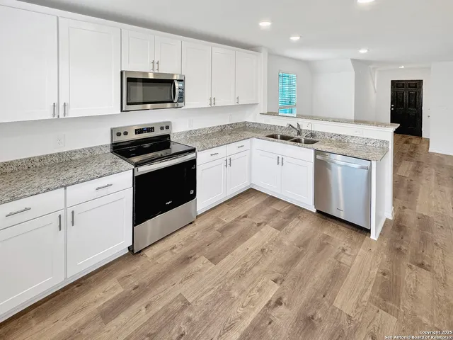 a white kitchen with granite countertop stainless steel appliances