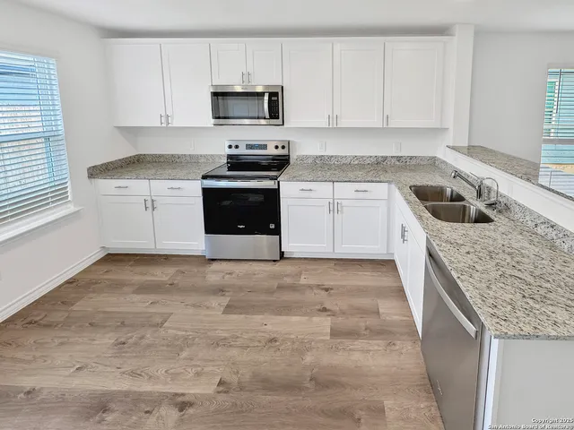 a kitchen with granite countertop a sink a stove and cabinets