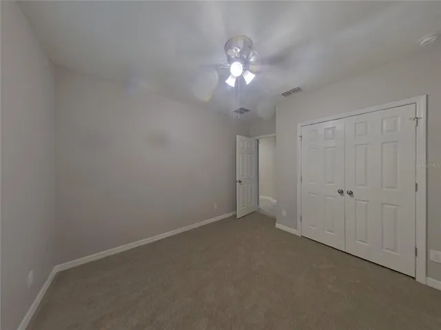 a view of an empty room with a chandelier fan