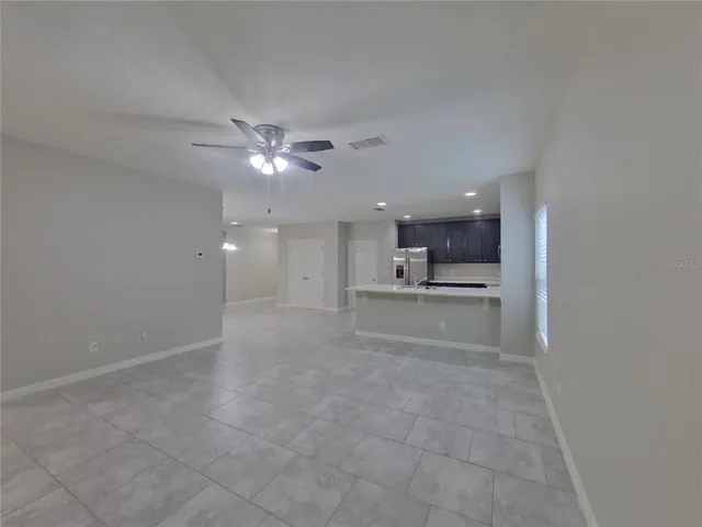 a view of an empty room and kitchen view