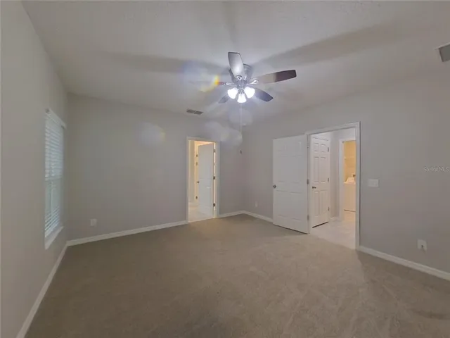 an empty room with a ceiling fan and a window