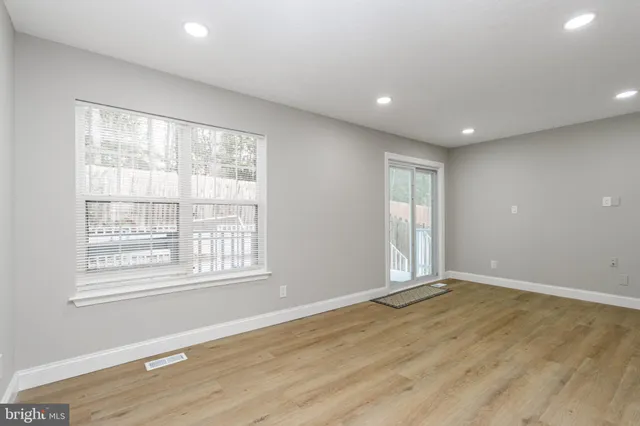 an empty room with wooden floor and windows