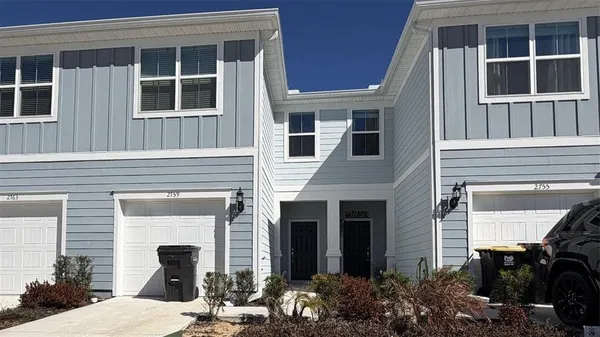 a view of a house with potted plants and a table and chairs