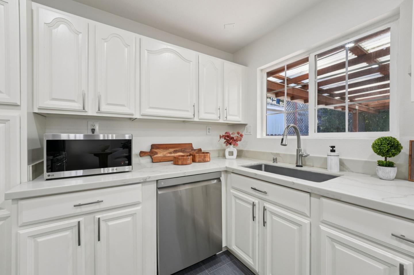 3336 Spring Street Redwood City, CA 94063 - Photo 16 of 40 a kitchen with stainless steel appliances granite countertop a sink a microwave a stove and white cabinets with wooden floor