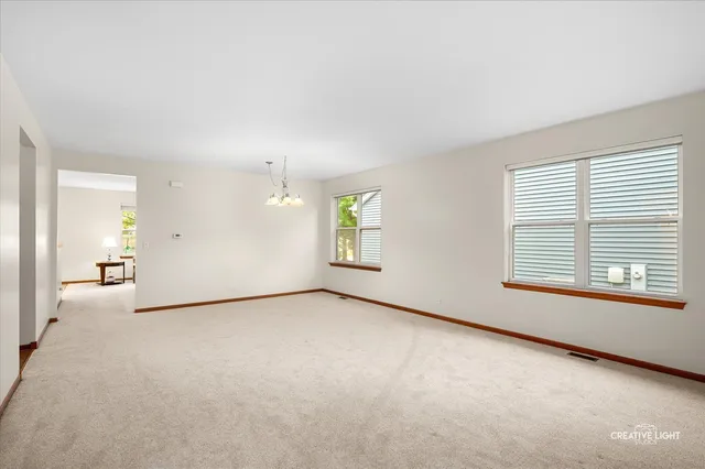 an empty room with chandelier fan and windows