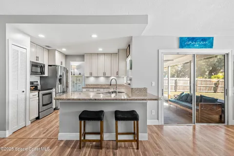 a kitchen with stainless steel appliances granite countertop a table chairs refrigerator and sink