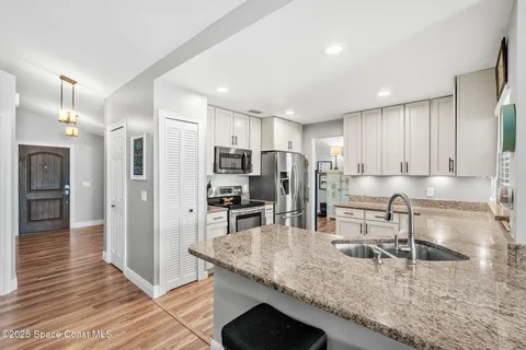 a kitchen with stainless steel appliances granite countertop a sink refrigerator and cabinets