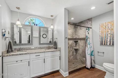 a bathroom with a granite countertop sink a mirror a toilet and a shower