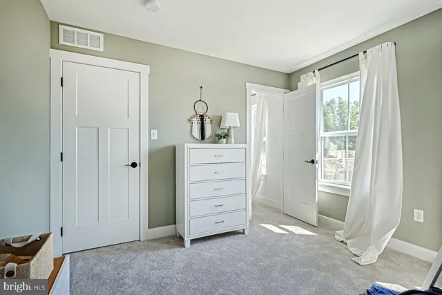 a view of an empty room with closet and a window