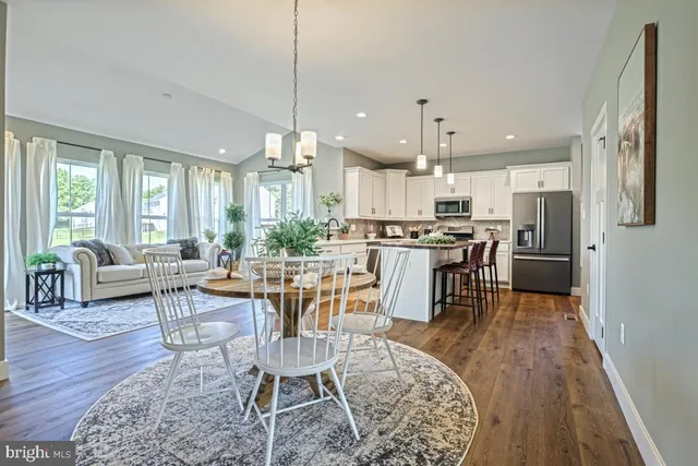 a dining room with stainless steel appliances kitchen island granite countertop a dining table chairs and view living room