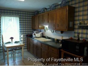 6097 Smithfield Road Godwin, NC 28344 - Photo 4 of 18 a kitchen with granite countertop a stove a sink dishwasher and cabinets with wooden floor