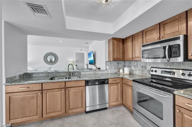a kitchen with granite countertop a sink stainless steel appliances and cabinets