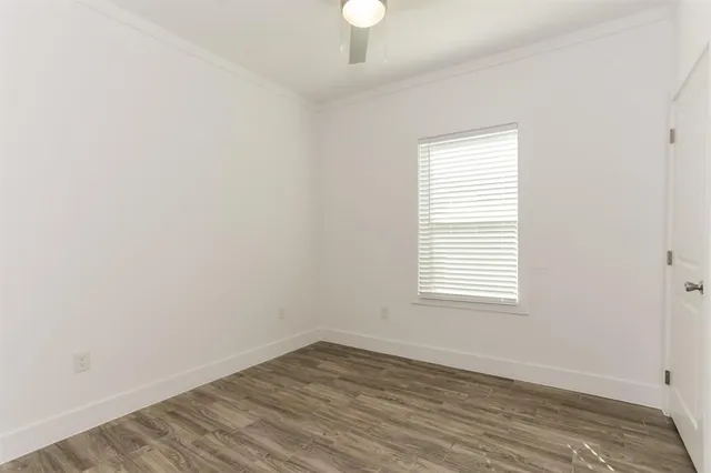 an empty room with wooden floor chandelier fan and windows