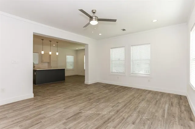 an empty room with wooden floor and a ceiling fan