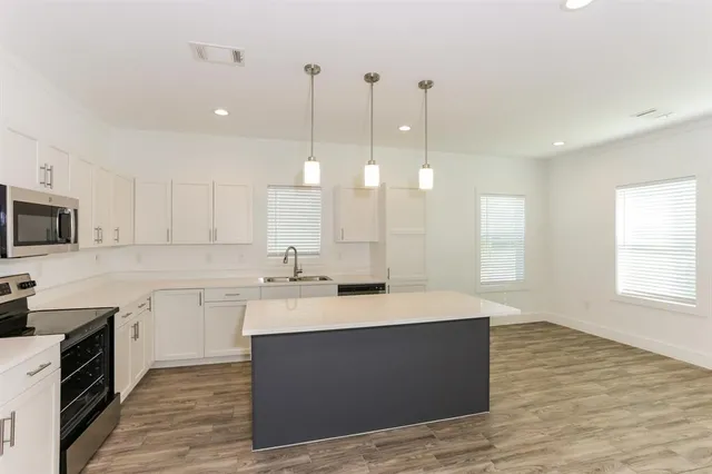 a large kitchen with stainless steel appliances kitchen island granite countertop a sink a stove a dining table and chairs