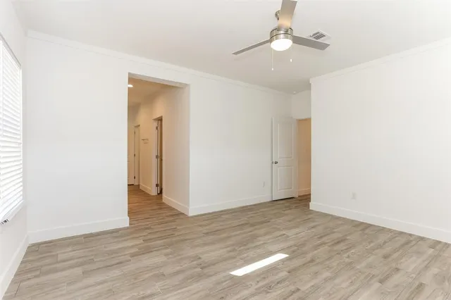 an empty room with wooden floor ceiling fan and window