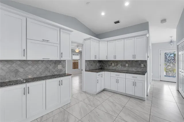 a kitchen with granite countertop white cabinets and white appliances