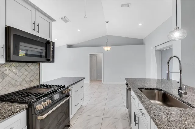 a kitchen with granite countertop a stove and a sink