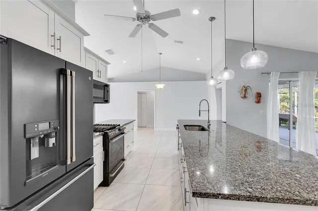 a kitchen with stainless steel appliances granite countertop a refrigerator a sink and a stove