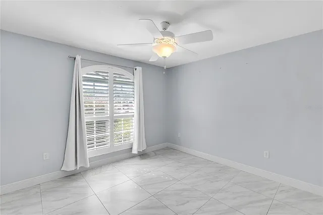 an empty room with windows and chandelier fan