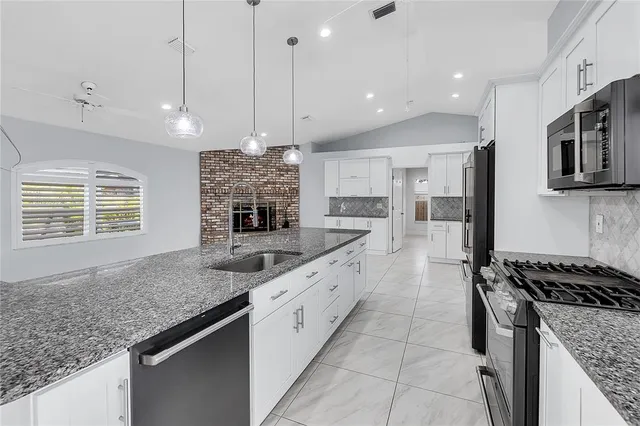 a kitchen with stainless steel appliances granite countertop a sink and a stove