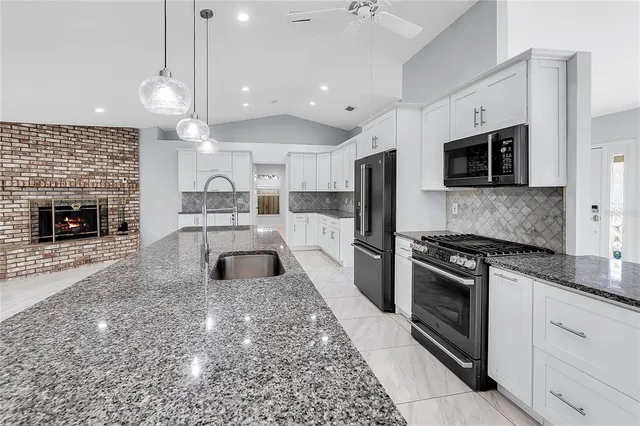 a large kitchen with granite countertop a stove a sink dishwasher a microwave oven and a stove with wooden floor