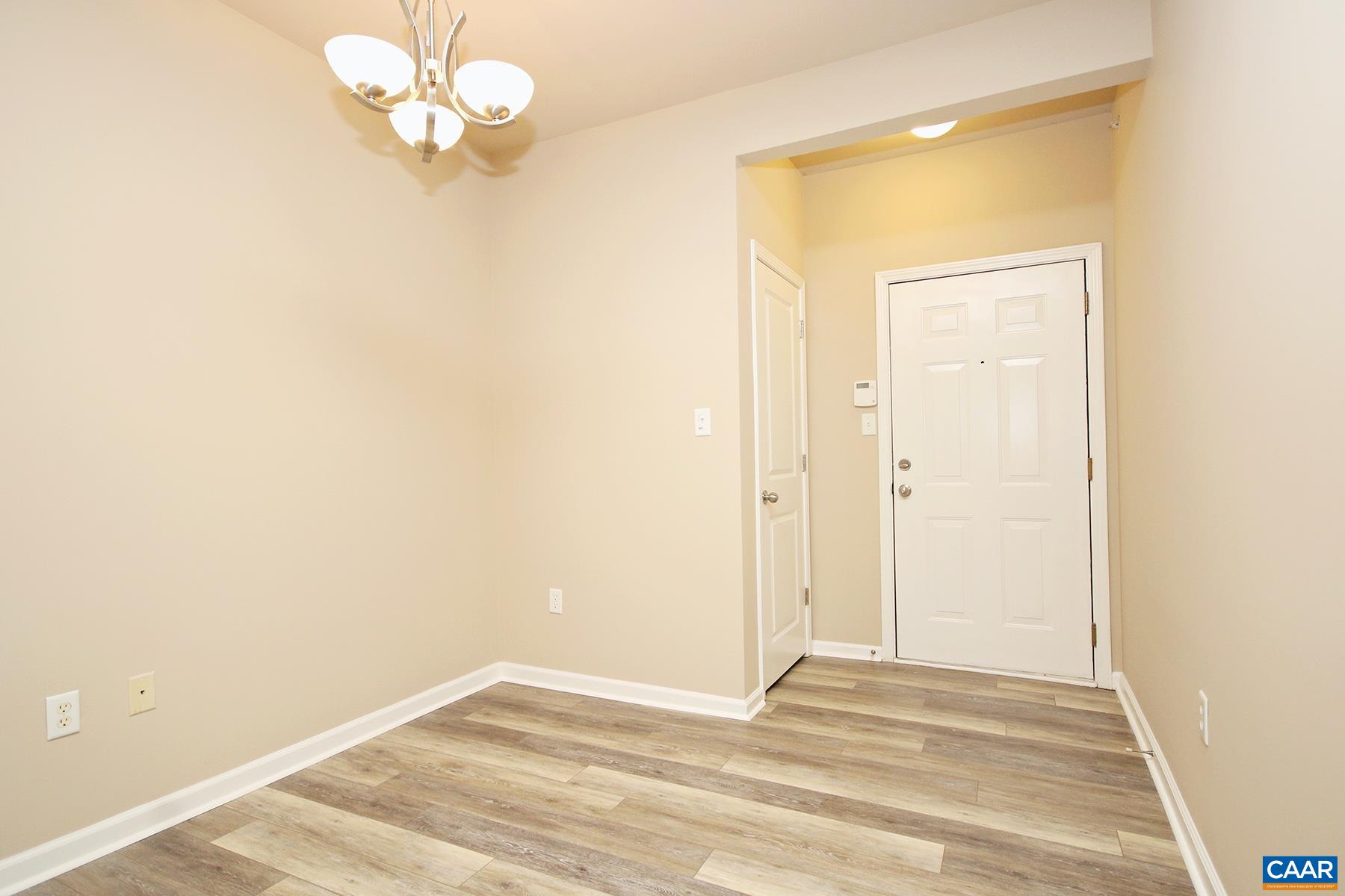735 Walker Square, Unit 3D Charlottesville, VA 22903 - Photo 3 of 12 an empty room with a chandelier fan and wooden floor