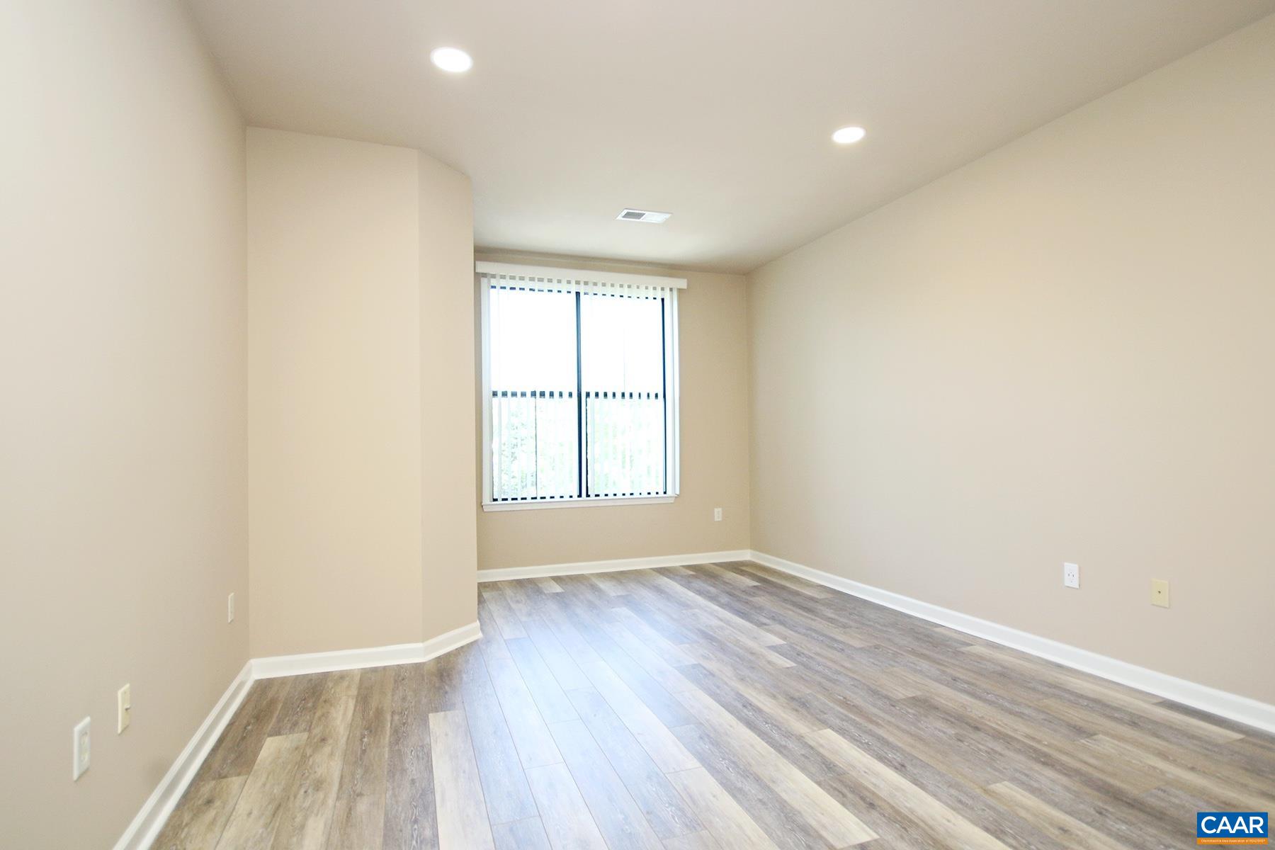 735 Walker Square, Unit 3D Charlottesville, VA 22903 - Photo 7 of 12 an empty room with wooden floor and windows