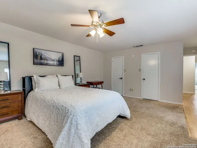 a bedroom with a large bed and a ceiling fan