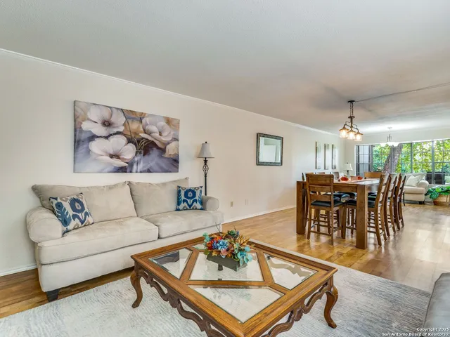 a living room with furniture and a dining table with wooden floor