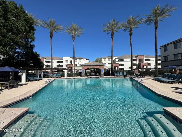 a view of a swimming pool with a lawn chairs under an umbrella