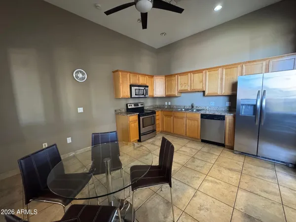 a kitchen with stainless steel appliances granite countertop a stove top oven a sink a dining table and chairs
