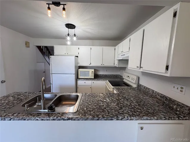 a kitchen with stainless steel appliances granite countertop a sink a stove a refrigerator a counter top space and cabinets