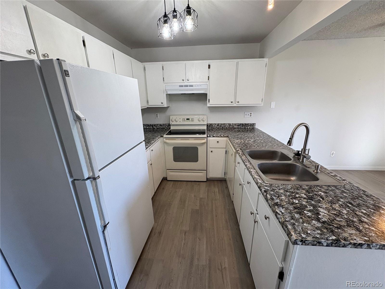 5505 Mansfield Court Colorado Springs, CO 80918 - Photo 5 of 14 a kitchen with granite countertop a refrigerator a sink a stove and white cabinets