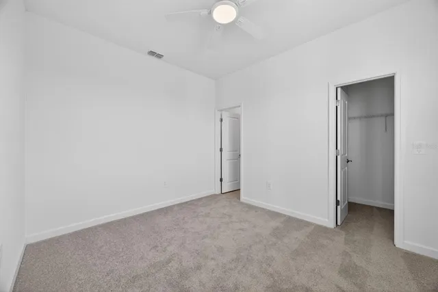 a view of an empty room and chandelier fan