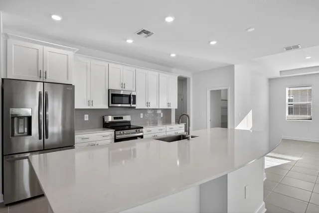 a kitchen with stainless steel appliances granite countertop a refrigerator a stove a microwave and white cabinets