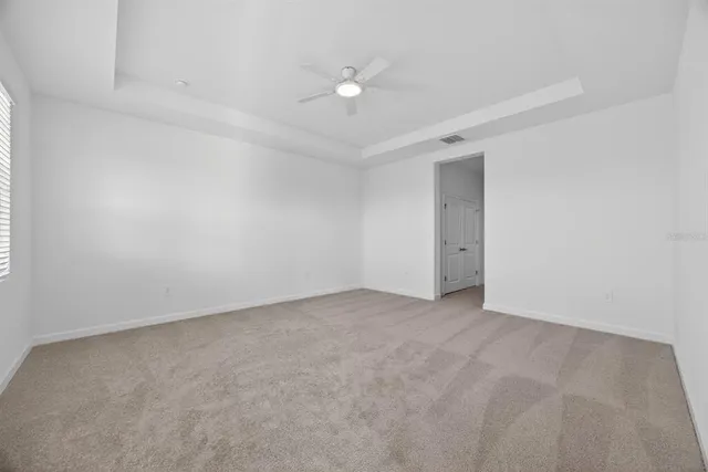 an empty room with a ceiling fan and window