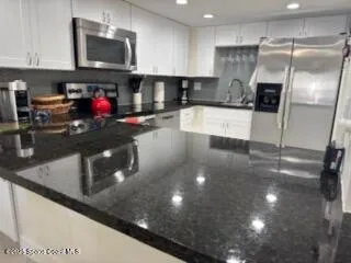 a kitchen with stainless steel appliances granite countertop a sink a stove and a refrigerator