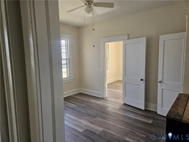 a view of a hallway with wooden floor and a ceiling fan