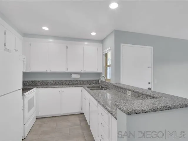 5978 Rancho Mission Road, Unit 264 San Diego, CA 92108 - Photo 5 of 22 a kitchen with granite countertop a sink and a white stove
